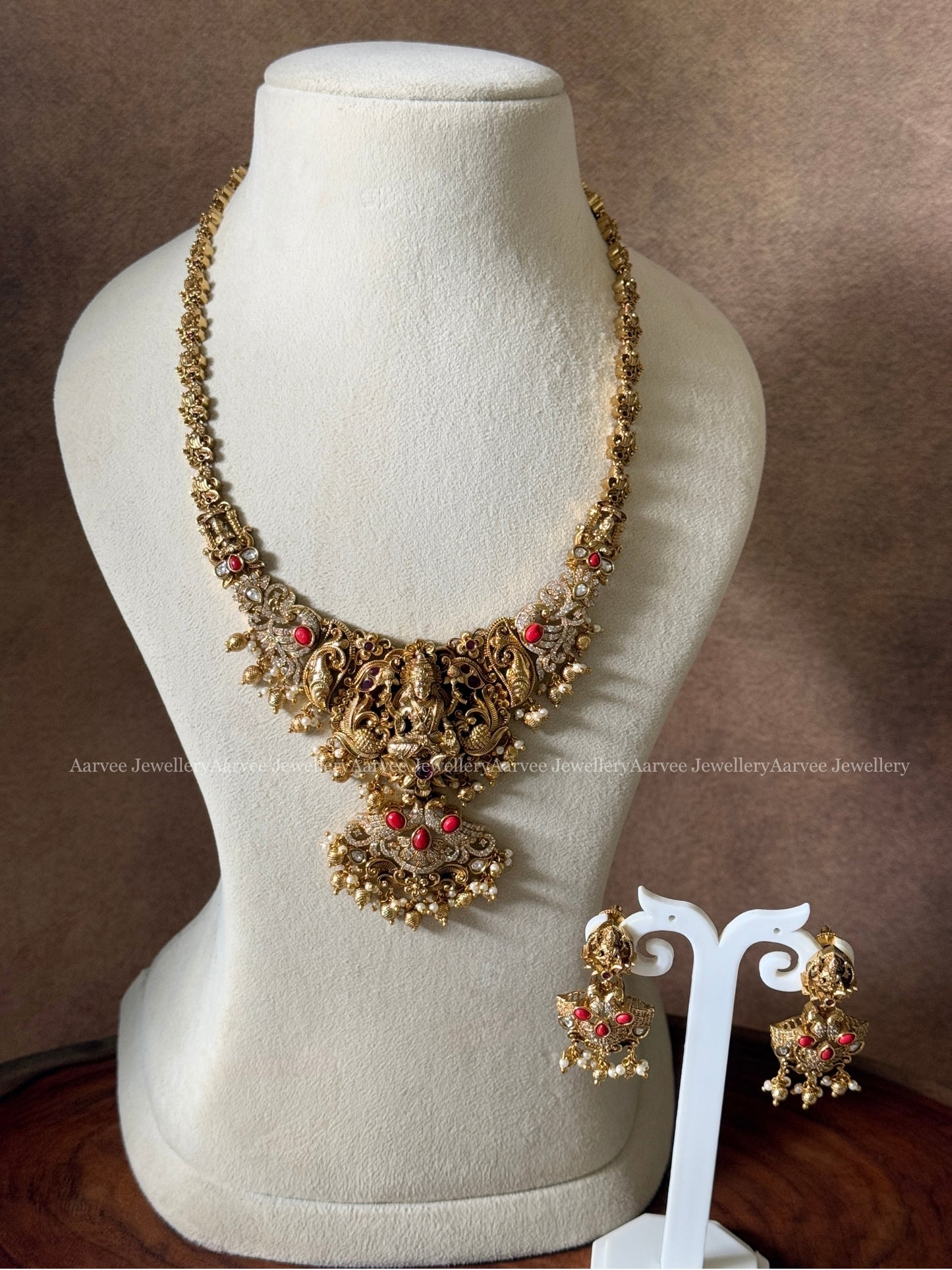 GOLD FINISH MID - LENGTH HARAM WITH LAKSHMI MOTIF AND CORAL STONE